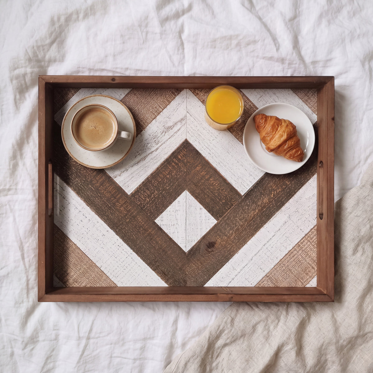 Houten dienblad met visgraatmotief met koffie, sinaasappelsap en croissant, ontbijt op bed