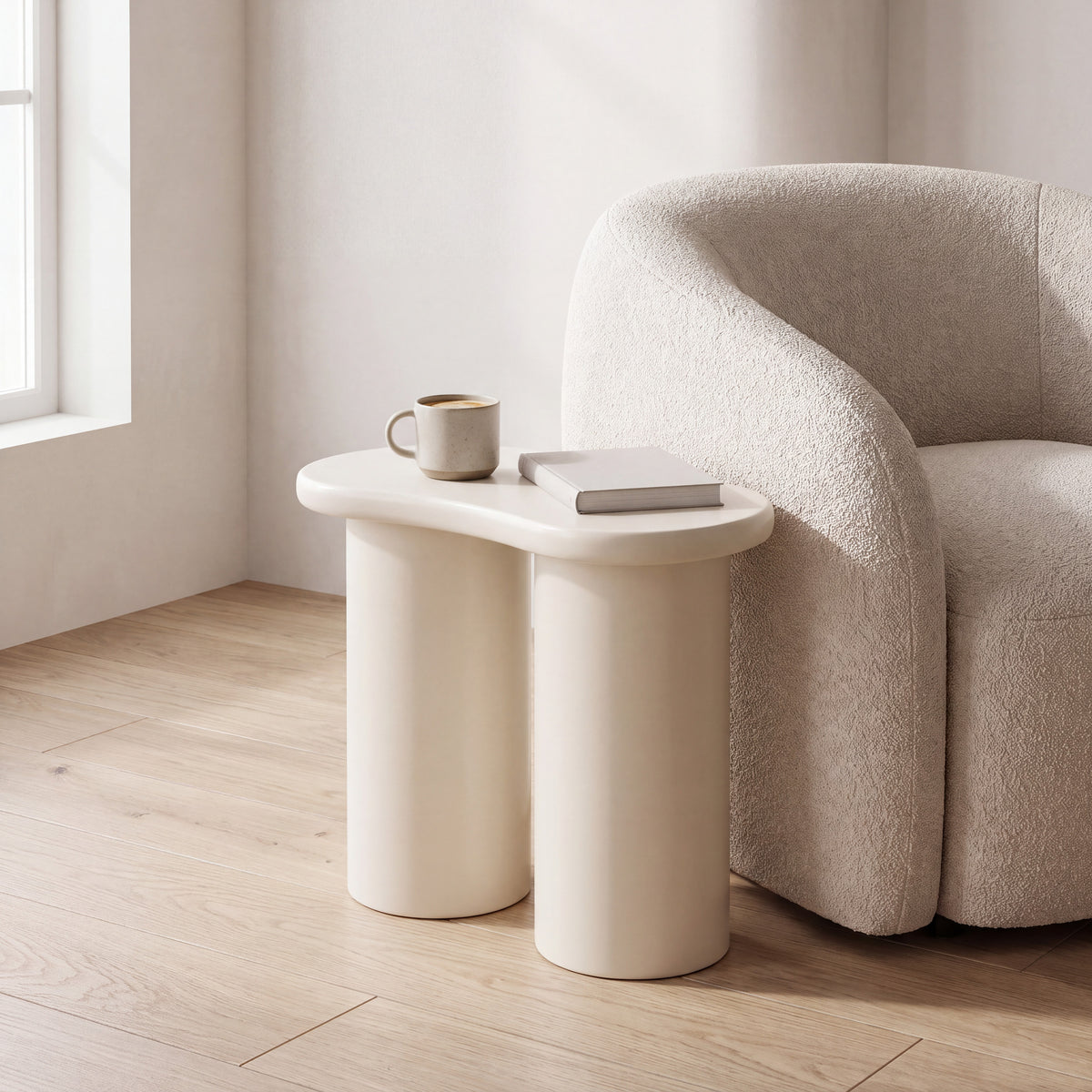 Liora Cloud bijzettafel in mat crème tegen de zijkant van een fauteuil, met koffie en een boek