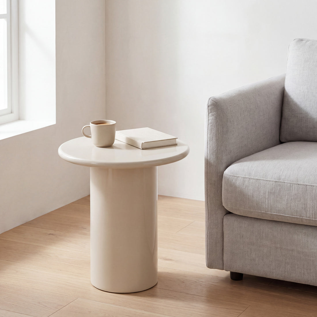 Liora ronde bijzettafel in hoogglans crème naast een fauteuil
