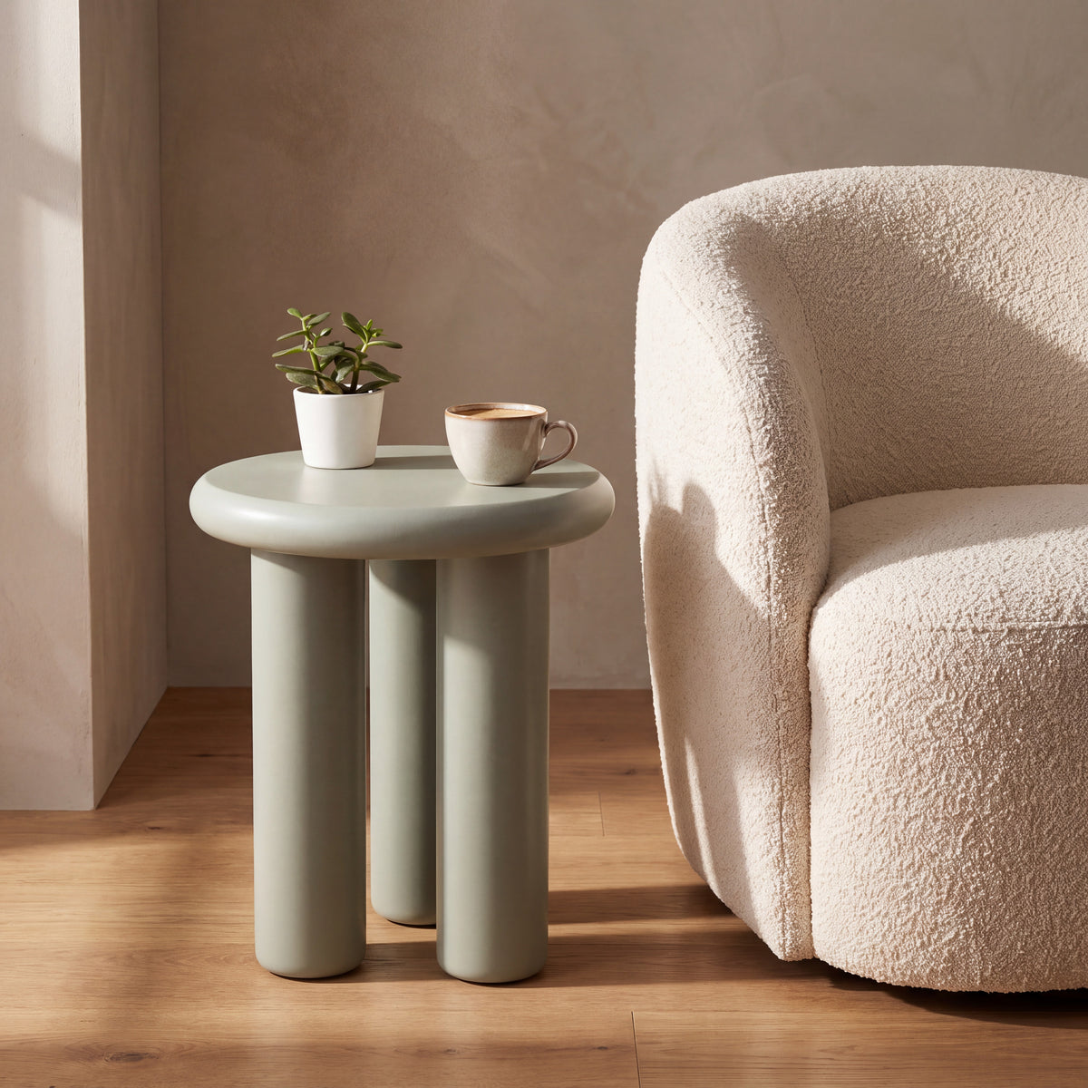 Liora bijzettafel in mat saliegroen naast een fauteuil, met plantje en koffie