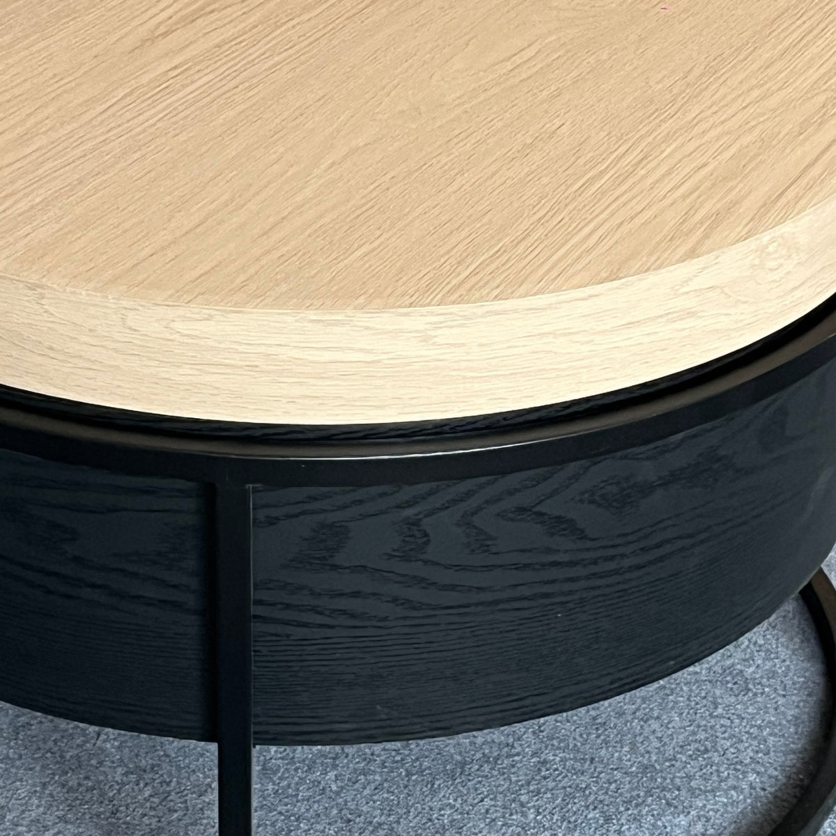 Close-up van het lichte eikenlook blad en de zwarte houtnerf van de ronde salontafel met opbergruimte