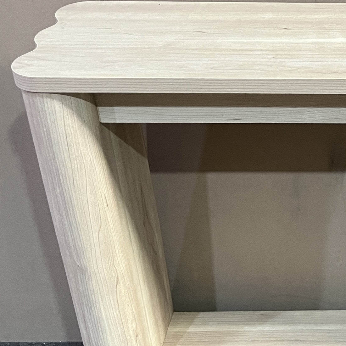 Close-up van het golvende blad, de ronde poot en de legplank van de sidetable