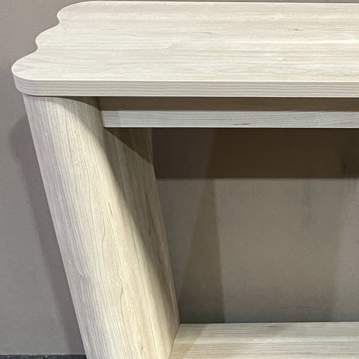 Close-up van het golvende blad, de ronde poot en de legplank van de sidetable